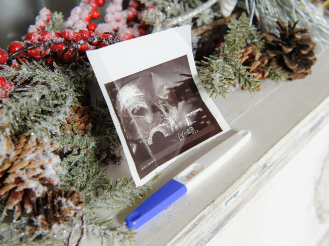 Ultrasound photo and pregnancy test on mantle with Christmas garland