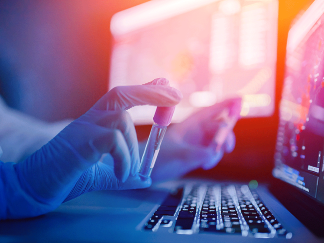 Hands holding test tubes at laptop