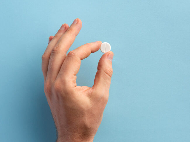 Hand holding white pill