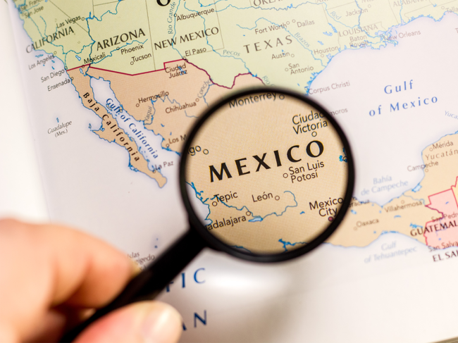 Magnifying glass over globe, focused on Mexico