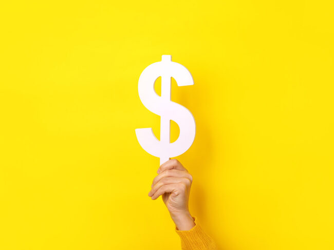 Hand holding dollar sign on yellow background