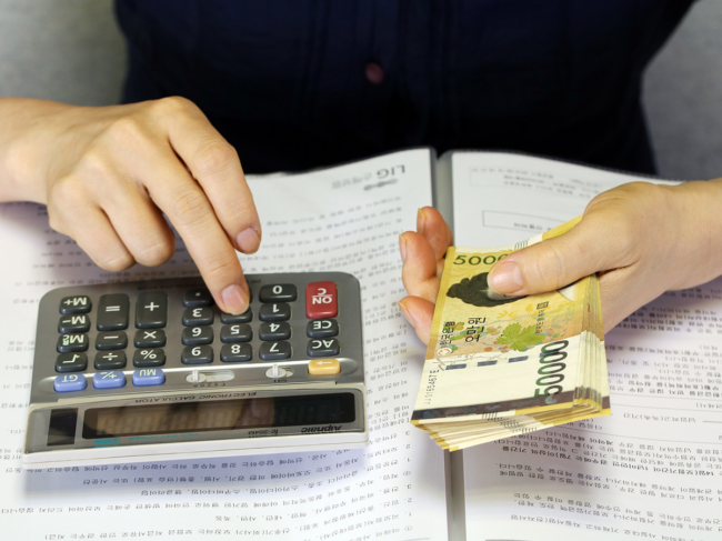 Person using calculator and holding Korean won