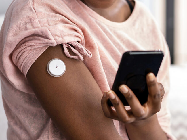 Woman wearing glucose monitor with smart phone