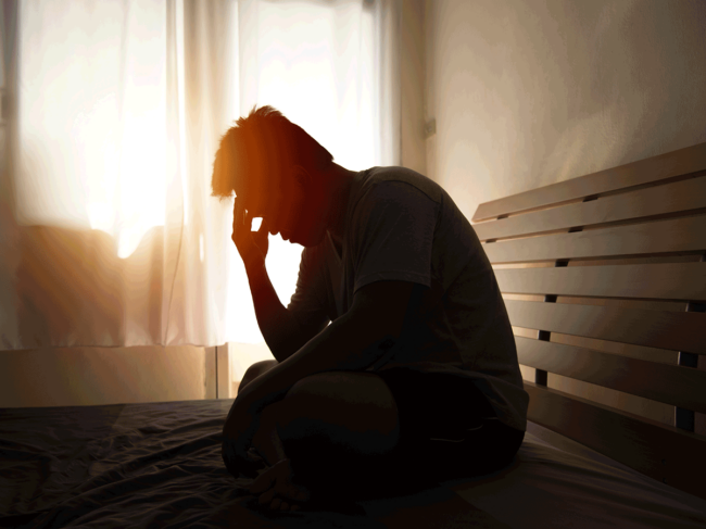 Man sitting on bed holding head