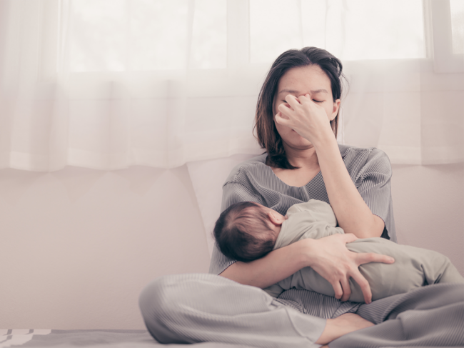 Tired mother holding newborn