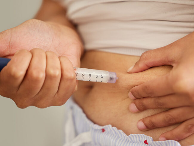 Person injecting medicine into abdomen