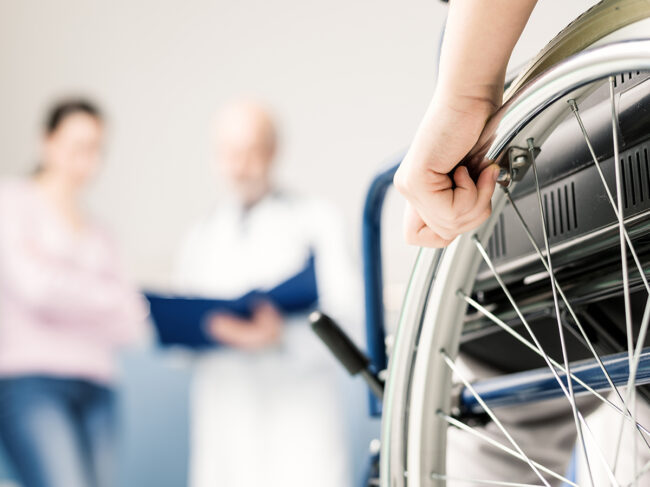 Child in wheelchair with parent, doctor