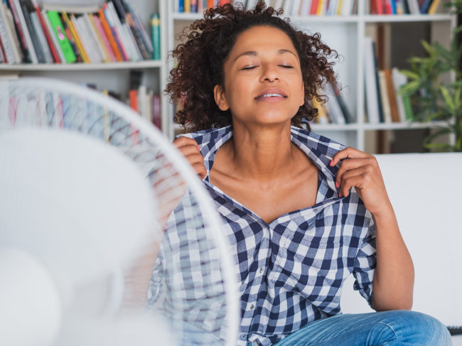 Woman cooling off in front of fan